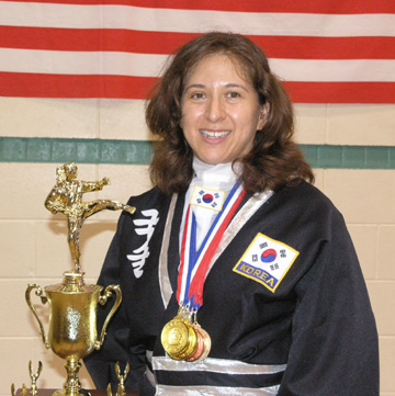 Photo of JKN Yvonne Jarique holding trophy and wearing medals.